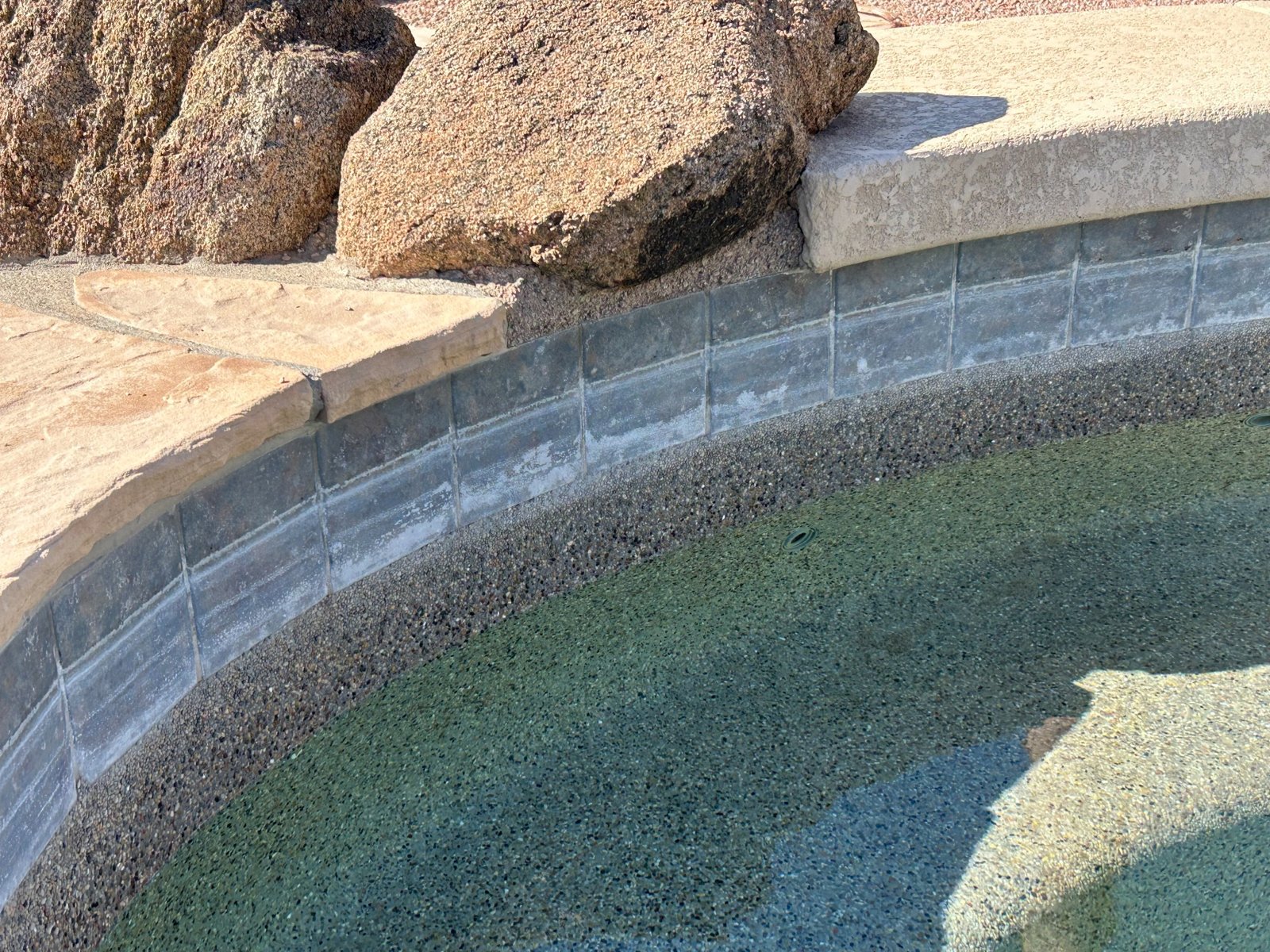 Before pool tile cleaning in Gilbert Arizona showing white calcium and mineral buildup on waterline tile